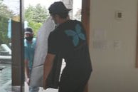 Delivery person wearing a Reverie t-shirt holding a mattress in front of a house entrance