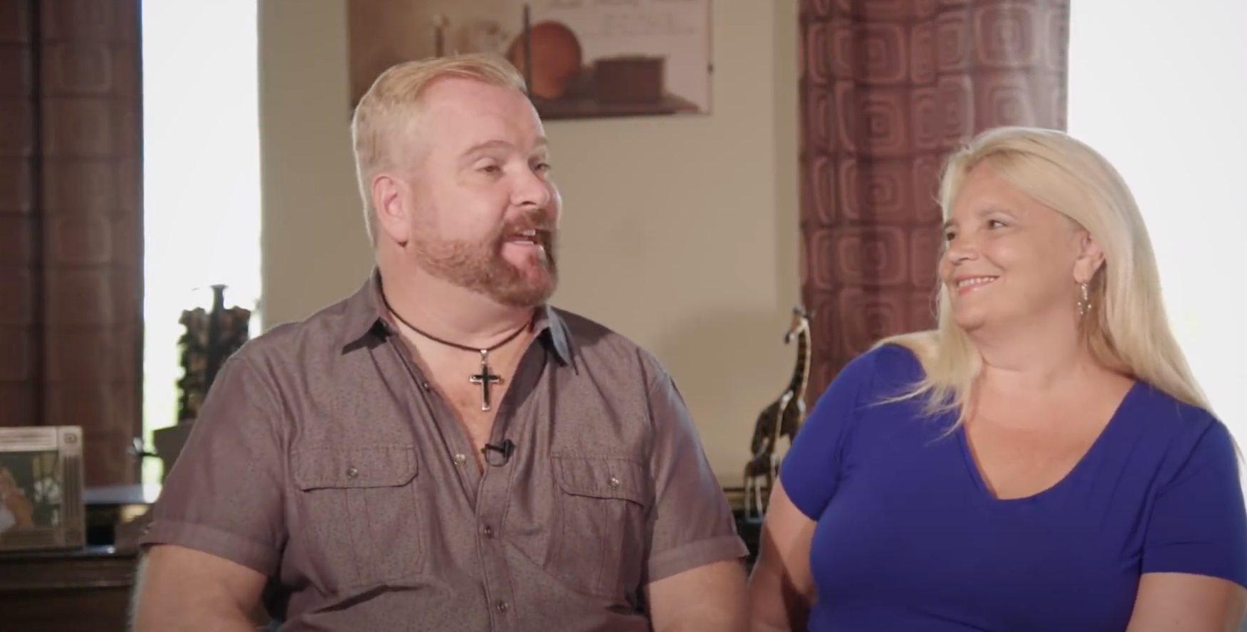 Two people sitting together in a room with decor in the background