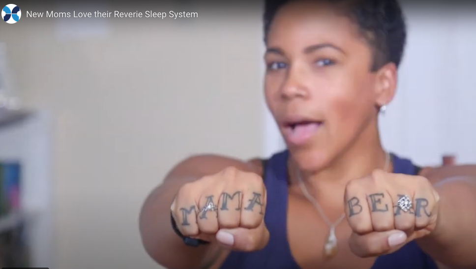 Woman with 'MAMA' and 'BEAR' tattoos on her fists in a promotional video for the Reverie Sleep System.