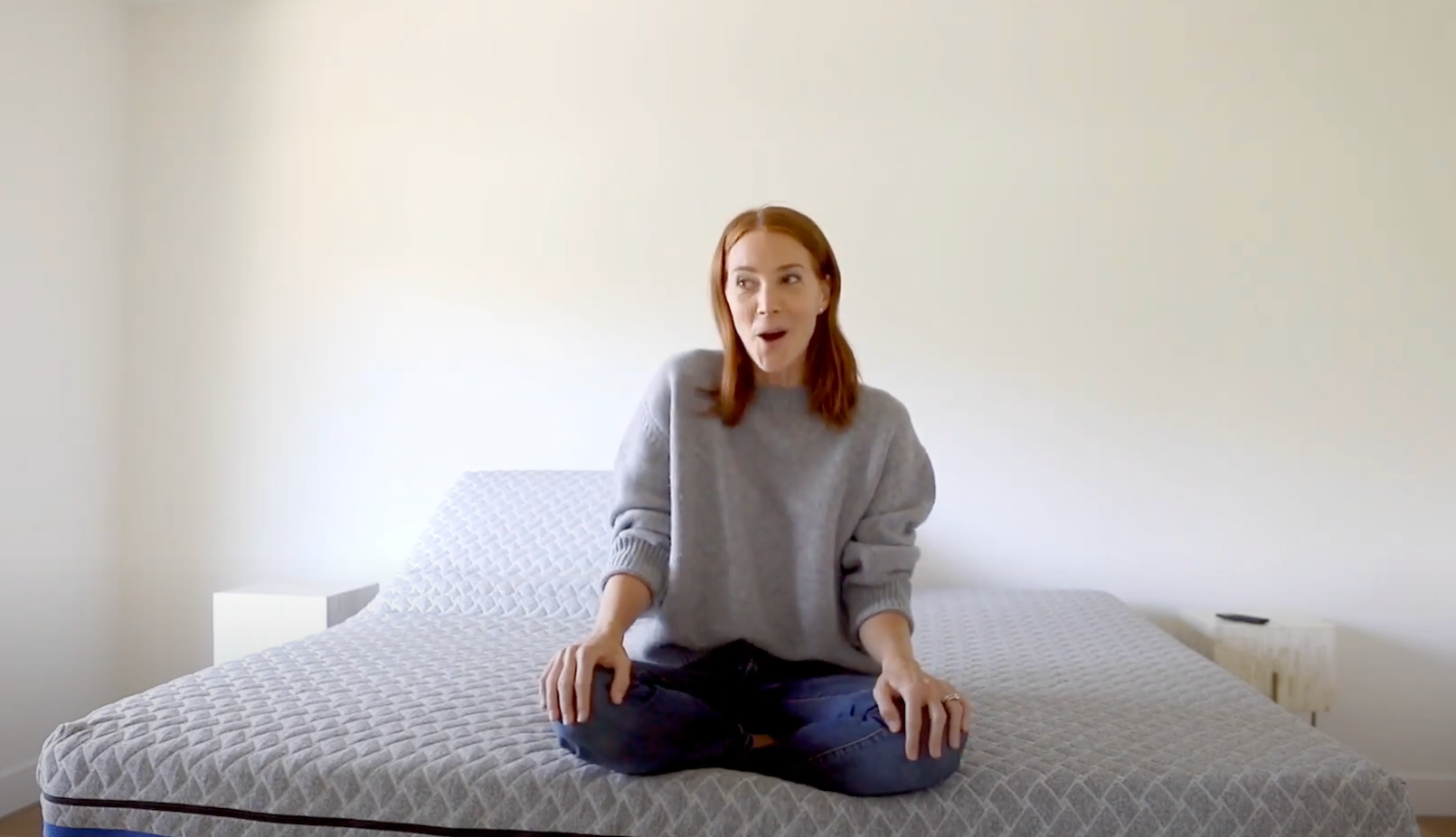 Person sitting on a mattress in a minimalistic room