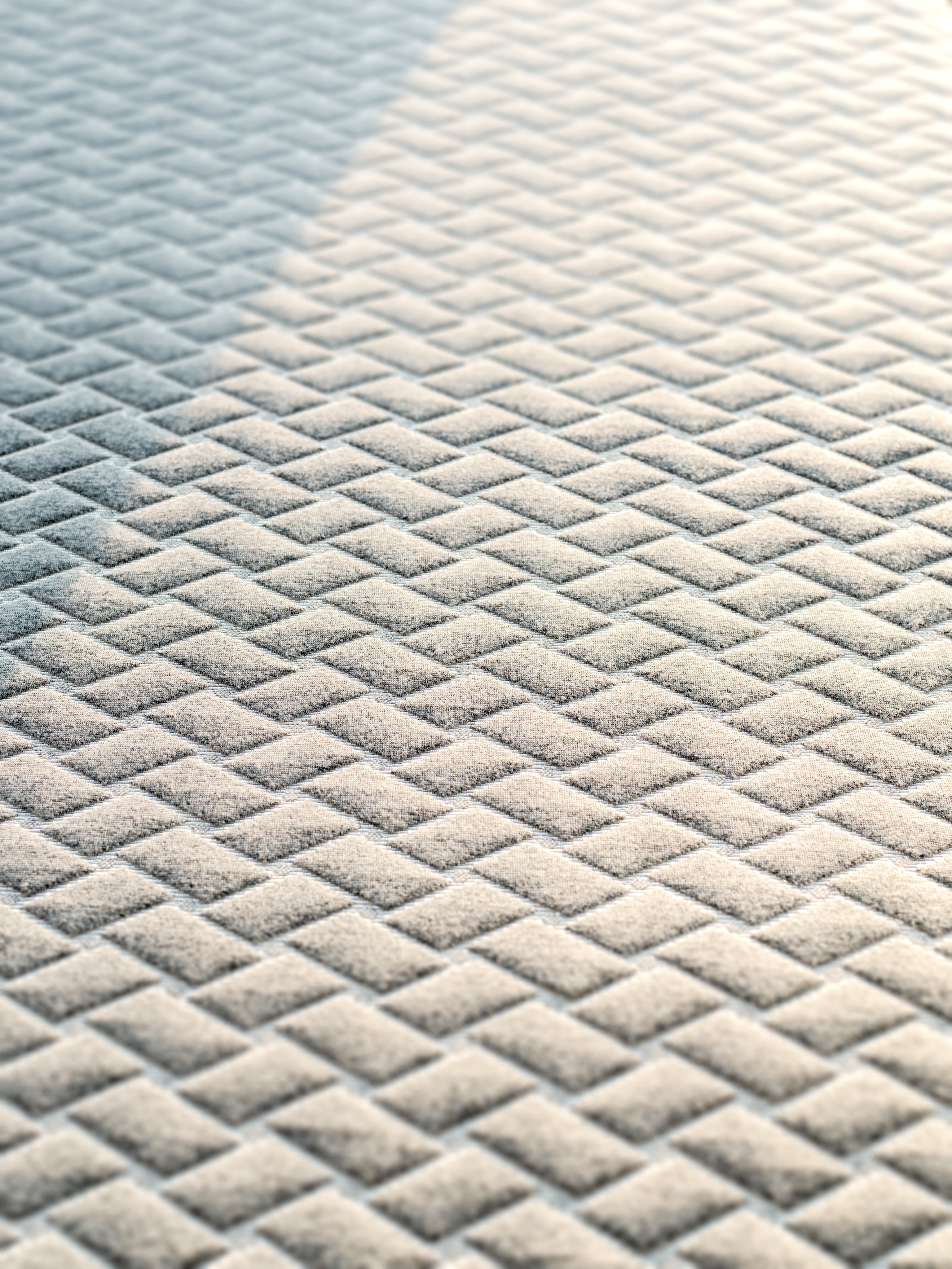 Close-up of a textured grey mattress cover with a geometric pattern